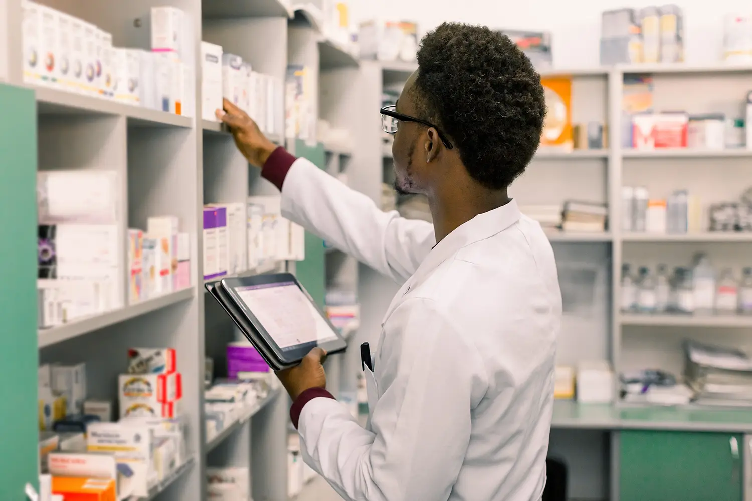 A man looks at boxes of medication on shelves in a pharmacy