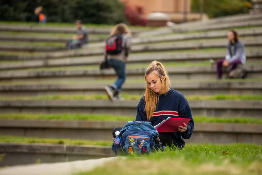 A student putting a book into her backpack