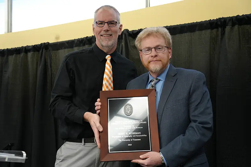 Derek Alderman accepts an award from Todd Moore at the Arts & Sciences Faculty Awards Ceremony in 2024
