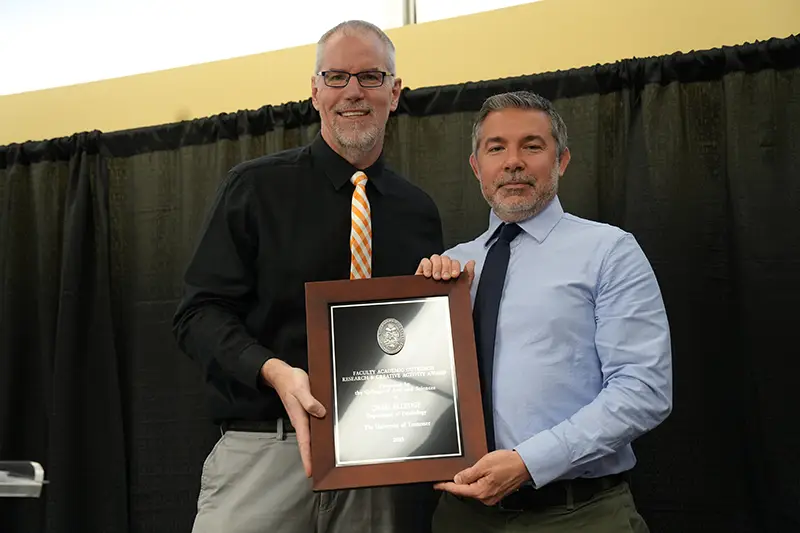 Chris Elledge accepts an award from Todd Moore at the Arts & Sciences Faculty Awards Ceremony in 2024