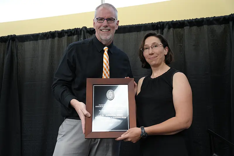 Laura Alexandra Russo accepts an award from Todd Moore at the Arts & Sciences Faculty Awards Ceremony in 2024