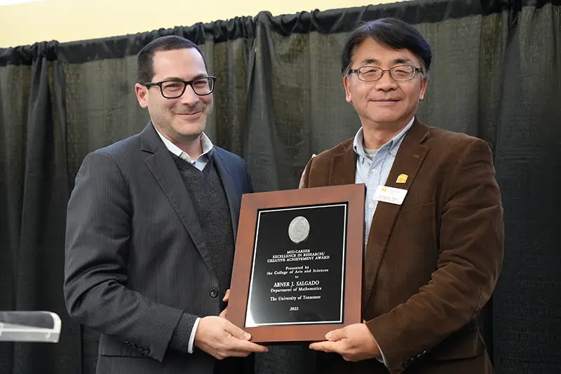 Abner Salgado accepts an award from Michael Blum at the Arts & Sciences Faculty Awards Ceremony in 2024
