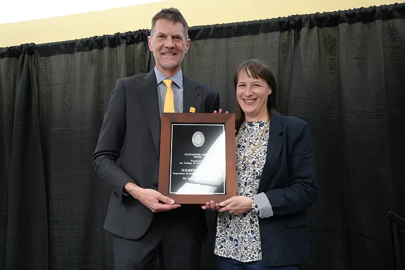 Elisabeth Schussler accepts an award from Robert Hinde at the Arts & Sciences Faculty Awards Ceremony in 2024