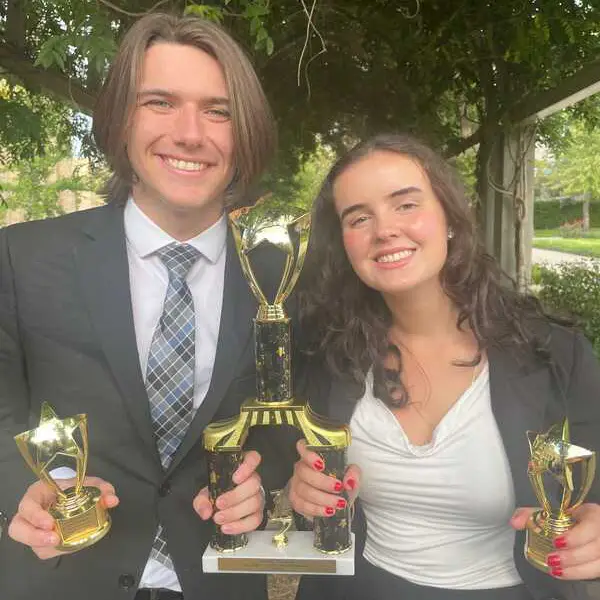 A male and female student pose for a photo with their awards