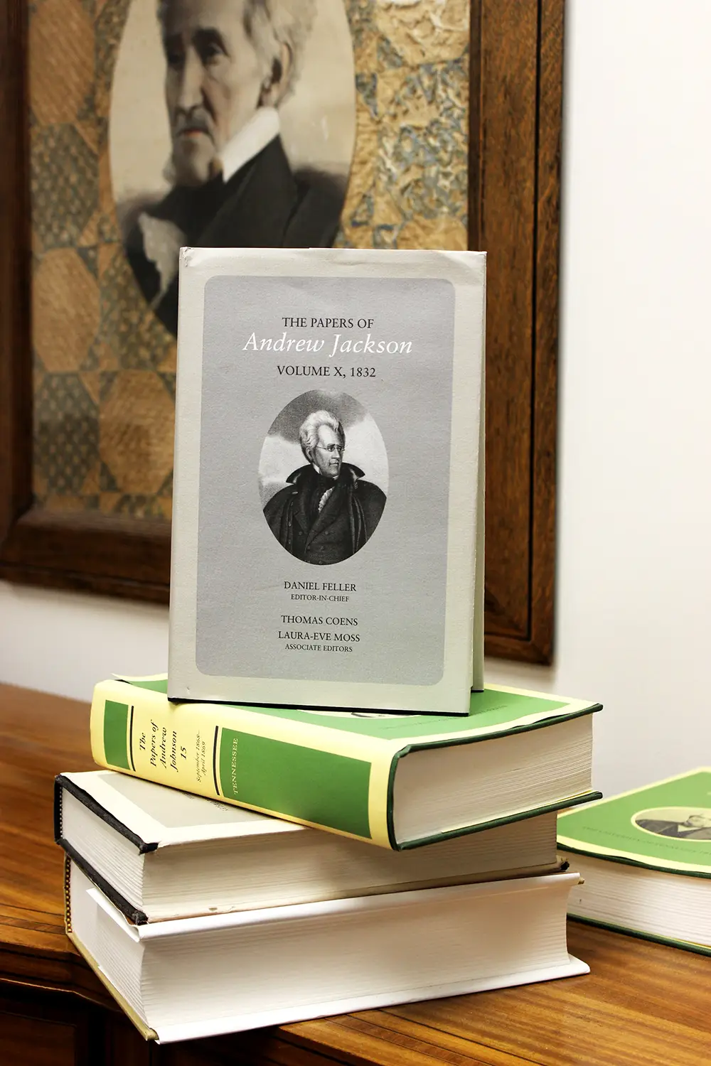 Book form of the Papers of Andrew Jackson on top of a stack of books with a painting of Jackson in the background