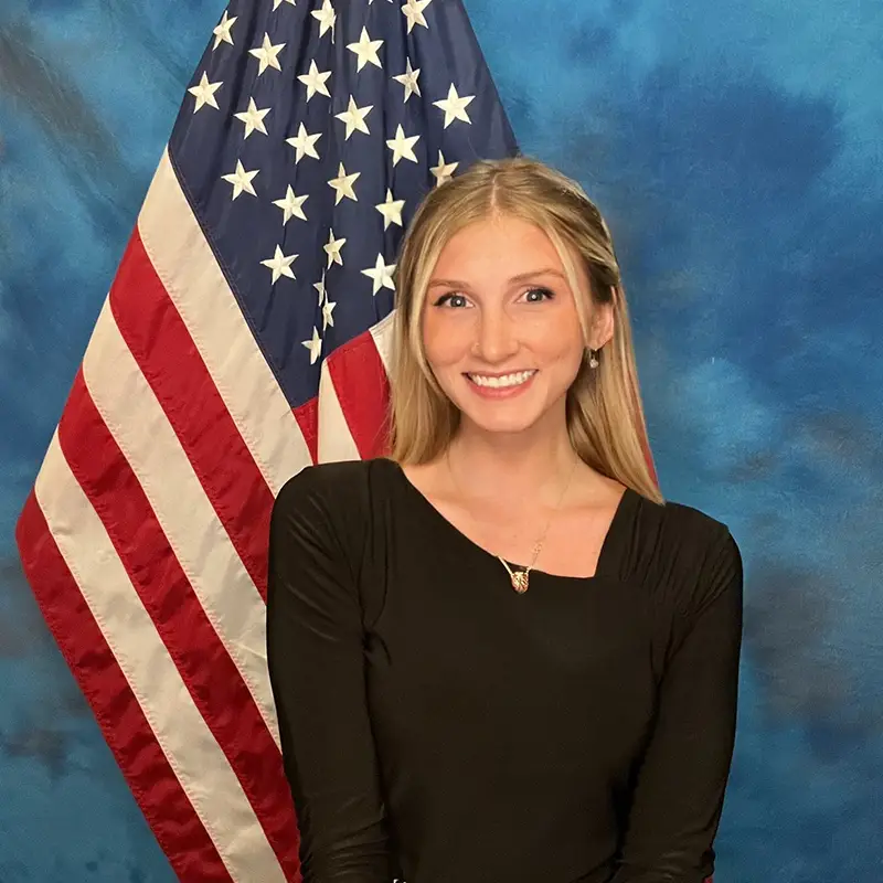 Headshot photo of Calista Boyd with the America flag on display behind her