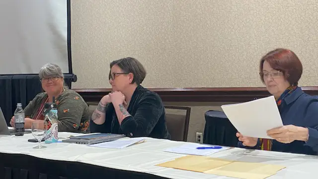 Three female speakers behind a table for a panel discussion