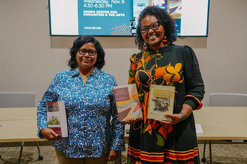 Two women posing for a photo while holding books