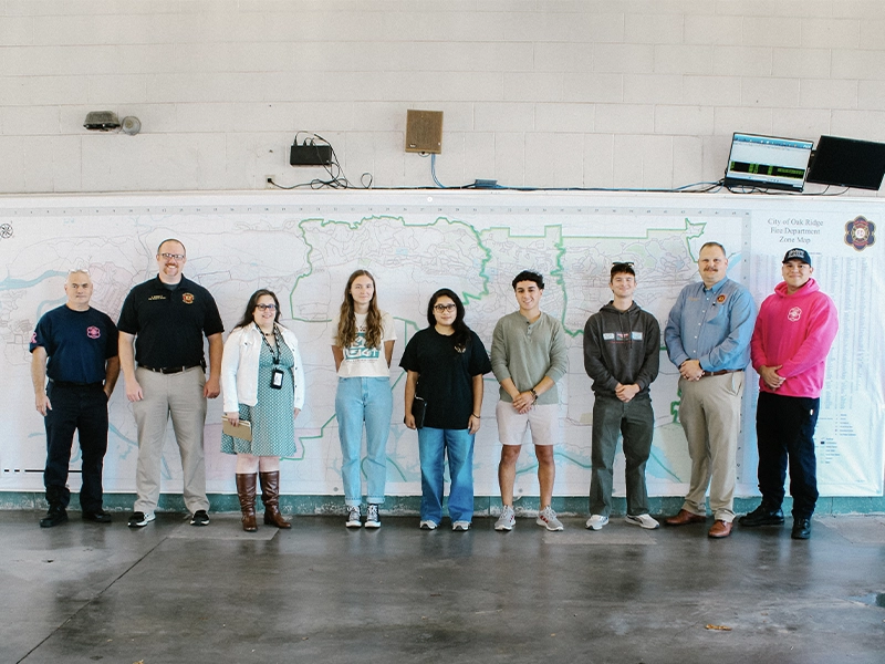 A line of people posing for a photo in front of a wall map