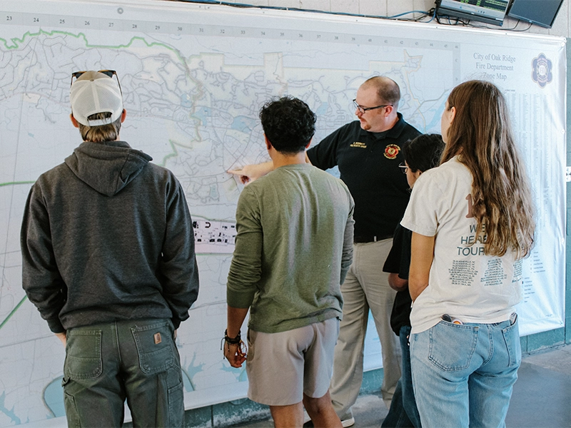 A man showing a wall map to three people