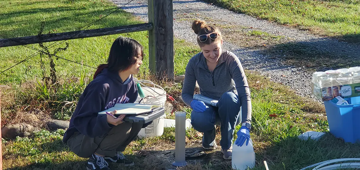 Students kneeling and taking water samples at a dairy farm