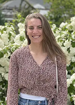 An outdoor photo of a woman with white flowers behind her