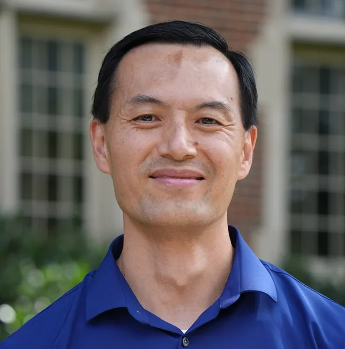 Outdoor headshot photo of a man in a blue shirt
