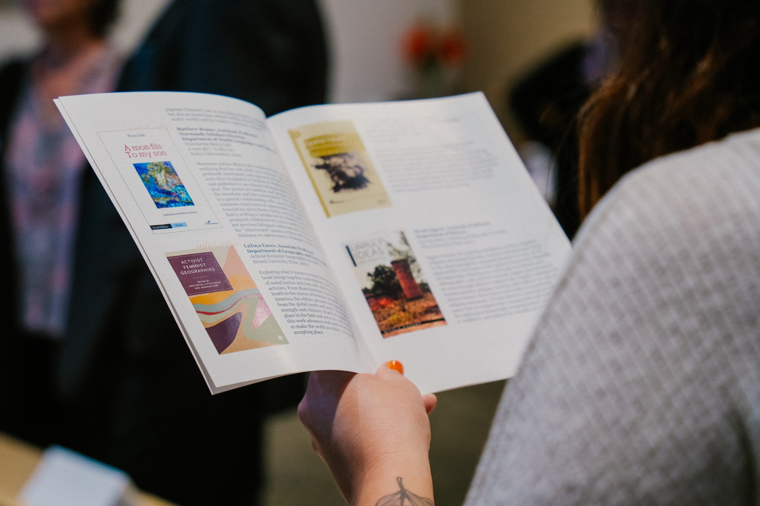 A participant holds a magazine from the DENBO Arts & Humanities Book Party