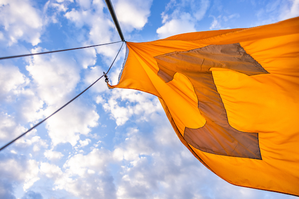 A University of Tennessee flag flies against a cloud-filled blue sky.