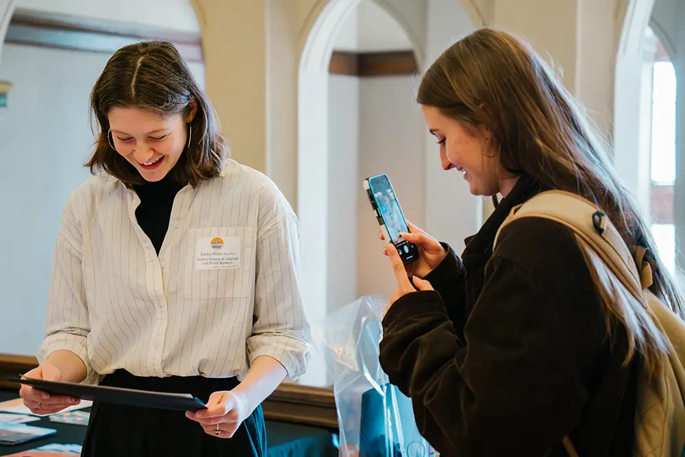 A student takes a photo of Emma C. Miller holding an award at the ASUReS event.