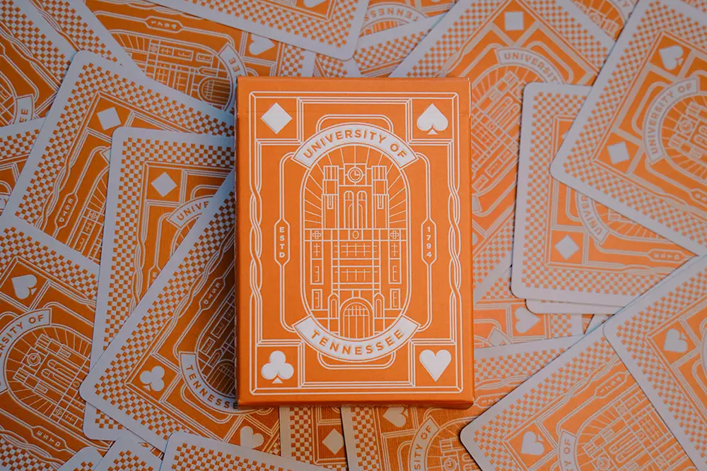 An exclusive orange UT playing card deck against a background of single deck cards.
