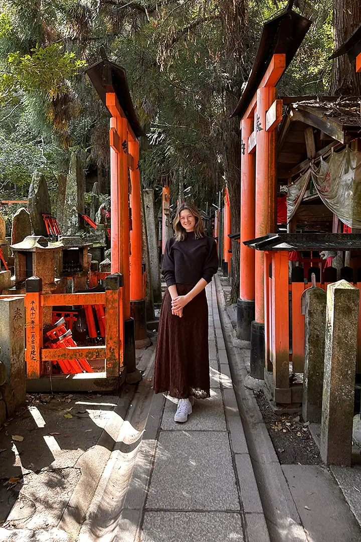 Emma Miller stands in Fushimi Inari, Kyoto surrounded by Japanese culture. 