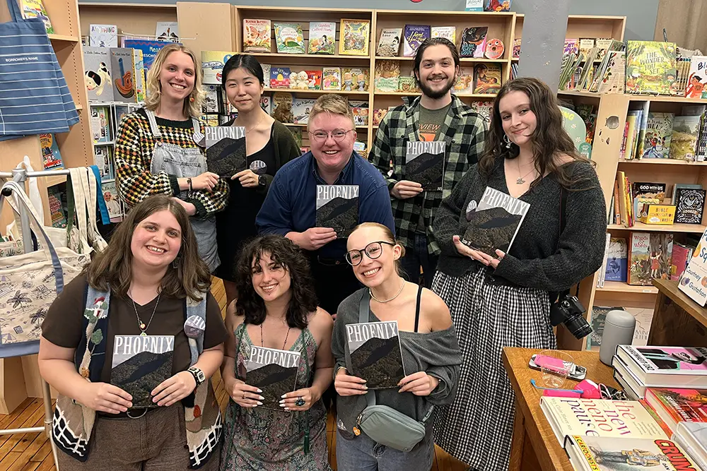 A group of students from the editorial team for the Phoenix Literary Magazine hold copies of the magazine. 