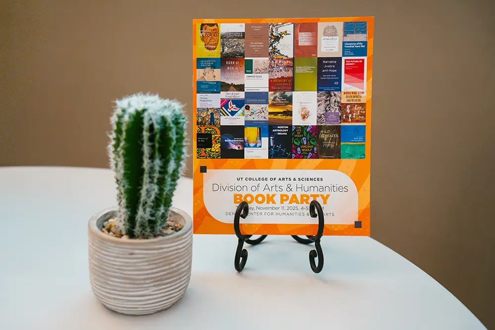 Snapshot of the Division of Arts and Humanities Book Party flyer next to a cactus in a pot. 