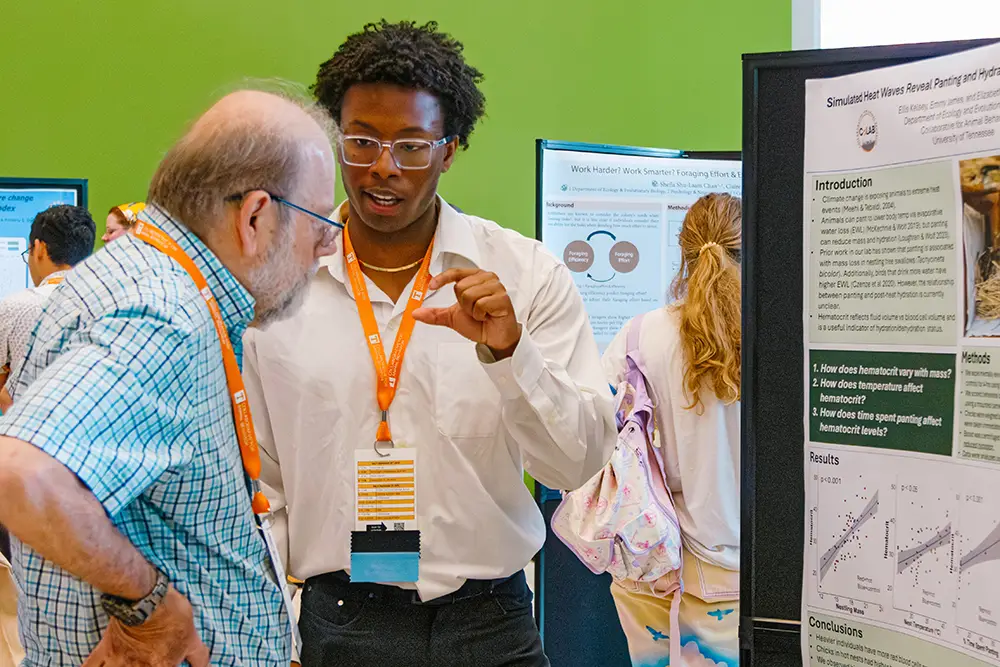 A student stands next o his posterboard as he presents his research to a professor during the Southeastern Conference for Animal Behavior (SeCAB). 