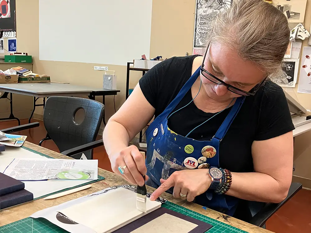 Tatiana Potts, a UT alumna, works on printmaking for one of her books. 