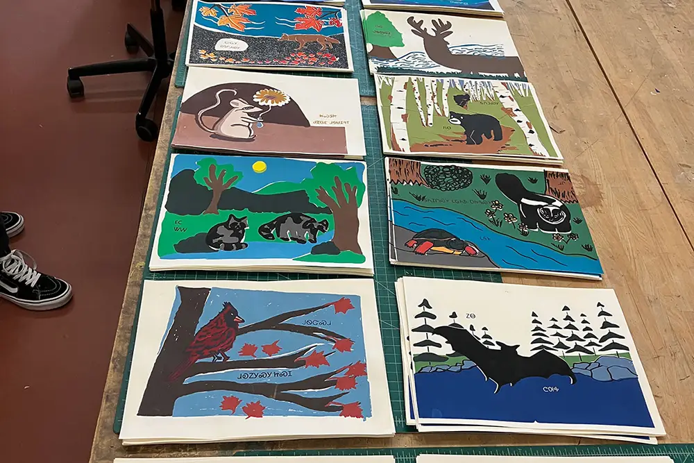 Various page layouts and spreads for bookbinding are displayed on a table side-by-side. The layouts contain images of nature. 