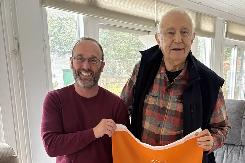Professor Brandon Prins holds a flag alongside Louay Bahry.