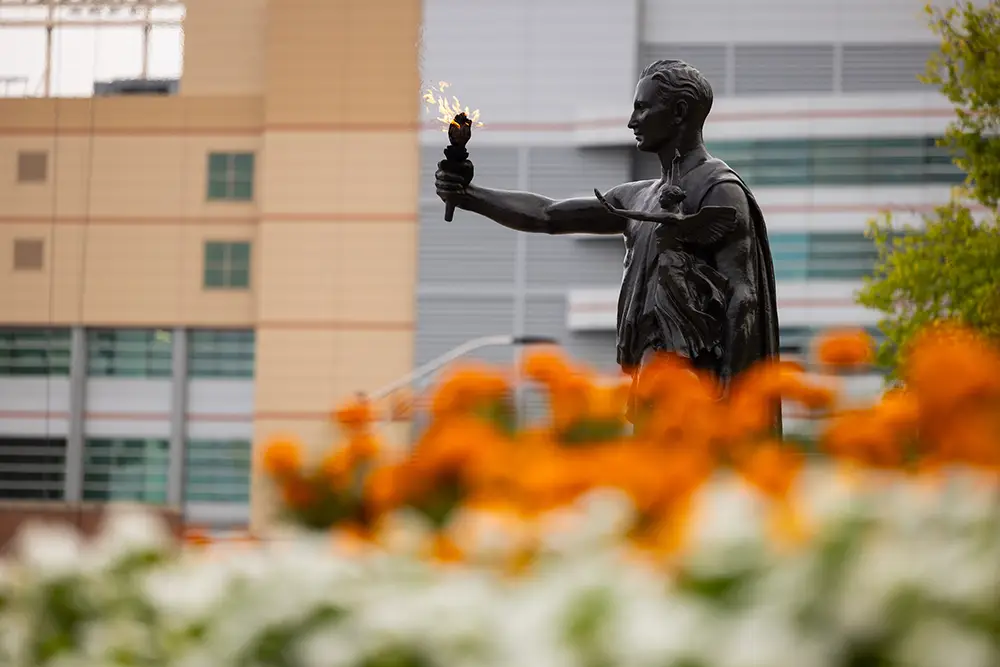 The Torchbearer with orange and white flowers in the foreground on September 11, 2023. Photo by Steven Bridges/University of Tennessee.