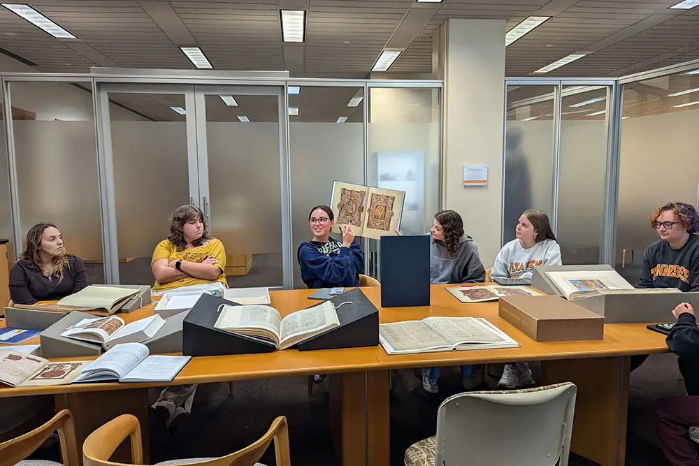 Medieval and Renaissance Studies students hold an old book from the Special Collections in Hodges Library.