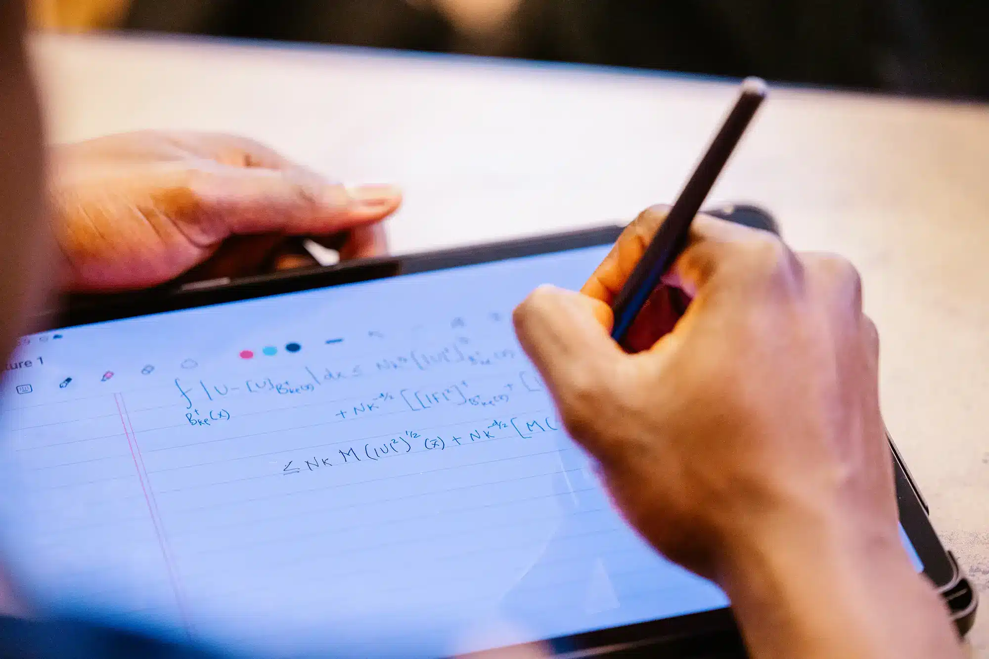 A person writing mathematical equations on a tablet